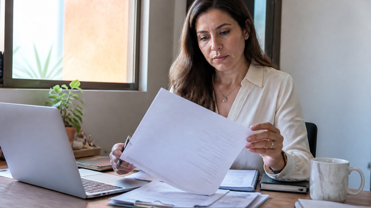 Professional reviewing translation quotation and documents at modern office desk with computer, coffee, and notepad in natural lighting